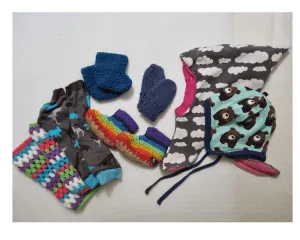 Baby wearing blankets, mittens, booties, and a snood