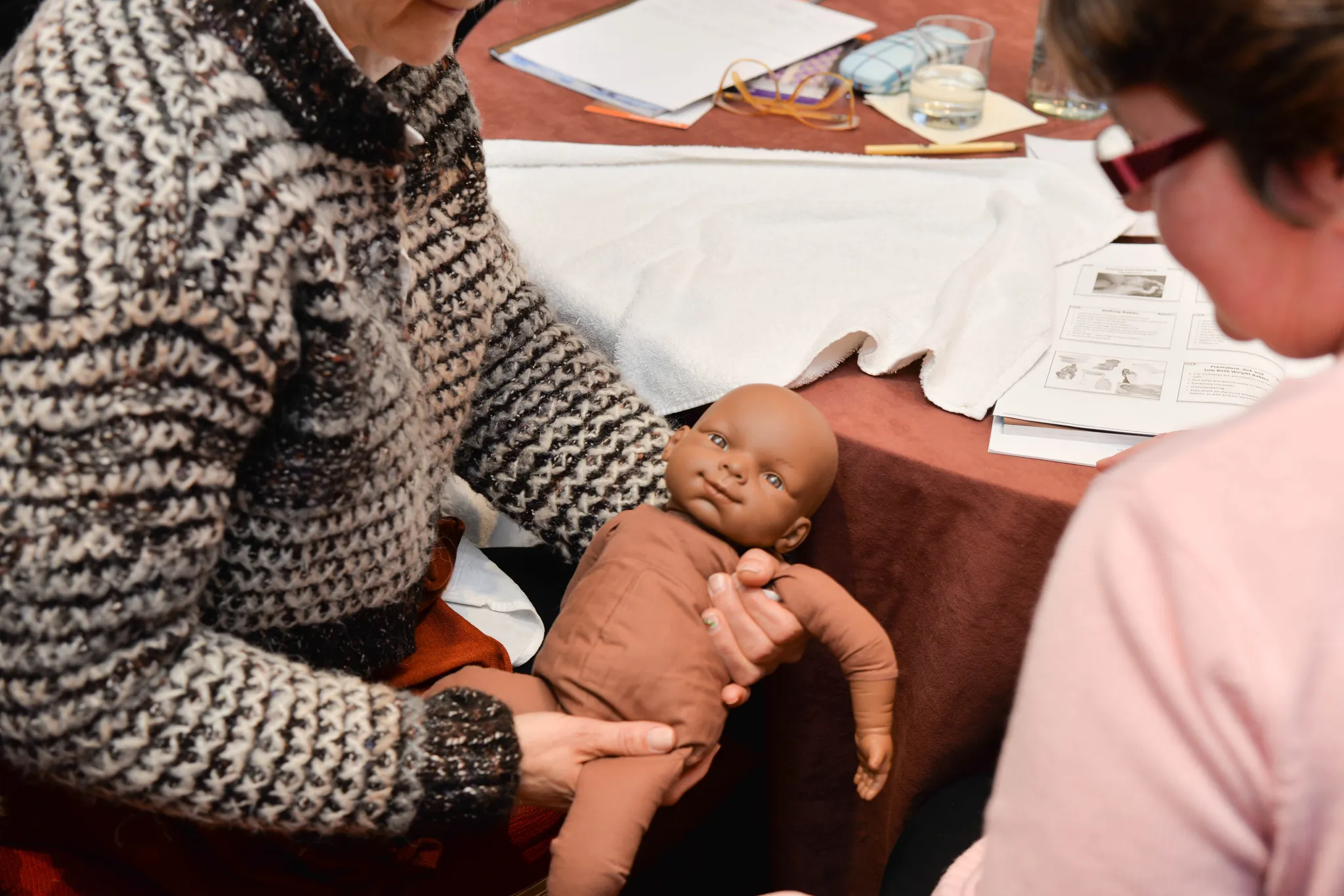 Practitioners handling a newborn doll during hands-on practical work